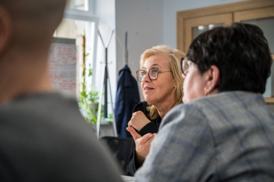 Darbnīcas dalībniece runā grupas diskusijā pie galda.